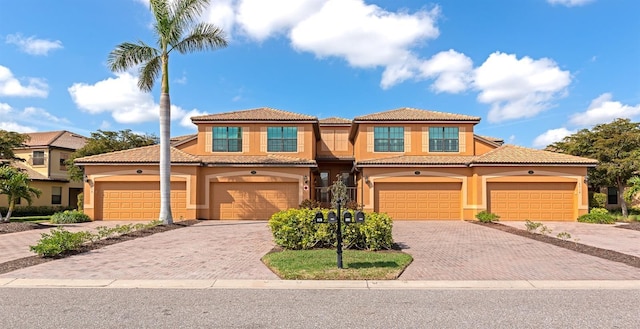 mediterranean / spanish home featuring a tile roof, decorative driveway, and stucco siding