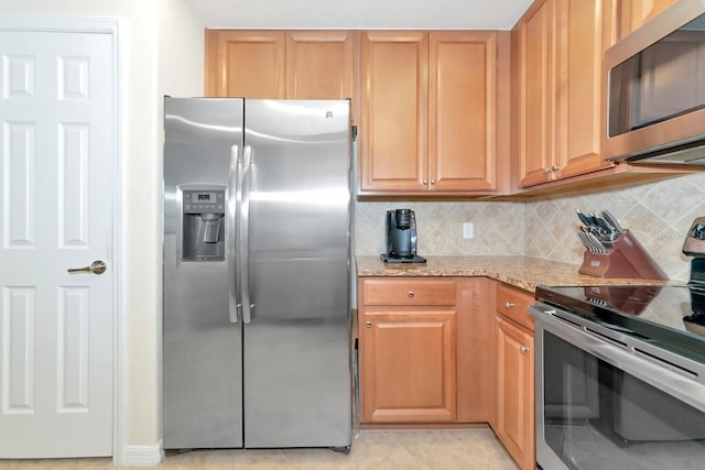 kitchen featuring stainless steel appliances, light tile patterned floors, light stone counters, and tasteful backsplash