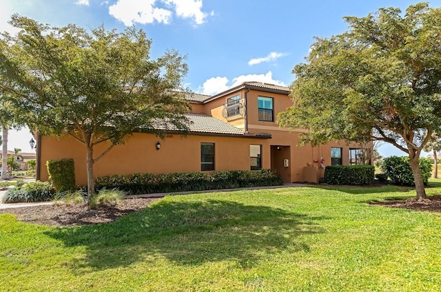 view of front facade with a tile roof, a front lawn, and stucco siding