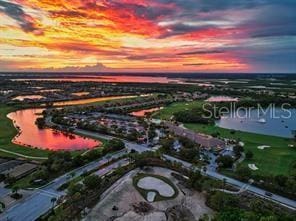 aerial view at dusk featuring a water view