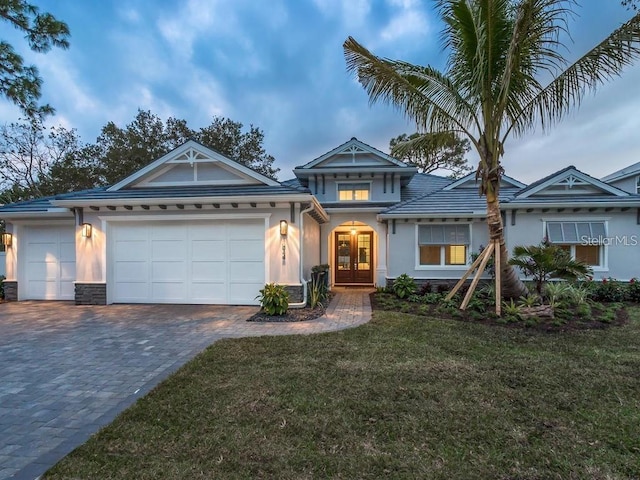 5103 Windward Ave, Sarasota, FL 34242 - view of front of property with french doors, decorative driveway, a garage, stucco siding, and a front lawn