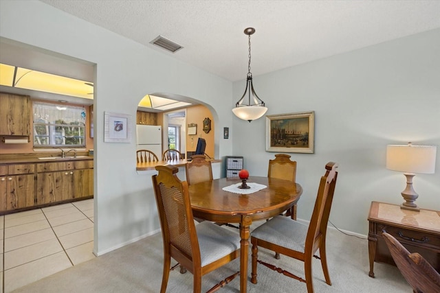 dining room featuring arched walkways, light tile patterned floors, a wealth of natural light, and visible vents