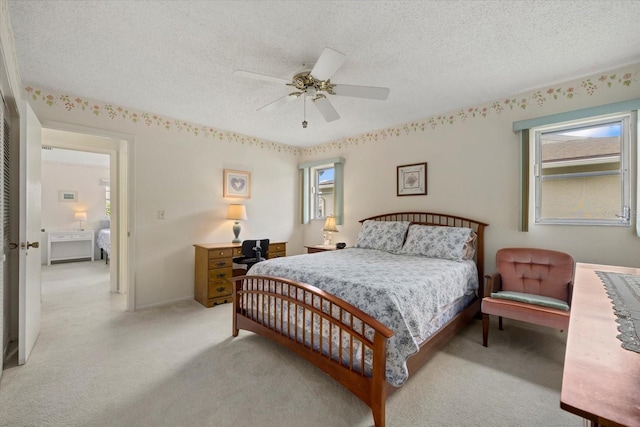 bedroom featuring light carpet, multiple windows, a ceiling fan, and a textured ceiling