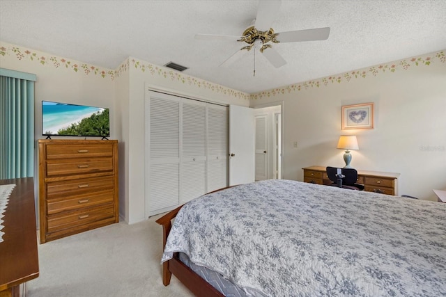 bedroom with a closet, visible vents, light colored carpet, ceiling fan, and a textured ceiling