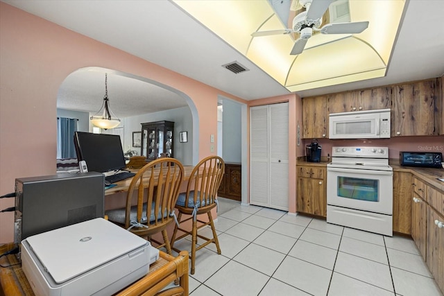 kitchen featuring white appliances, brown cabinetry, and visible vents