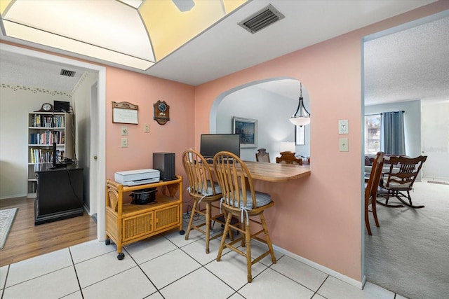 office space featuring arched walkways, light tile patterned floors, visible vents, and baseboards