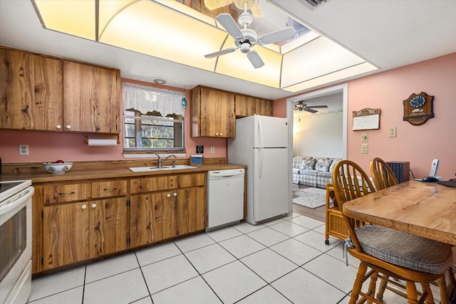 kitchen with white appliances, ceiling fan, brown cabinets, a sink, and light tile patterned flooring