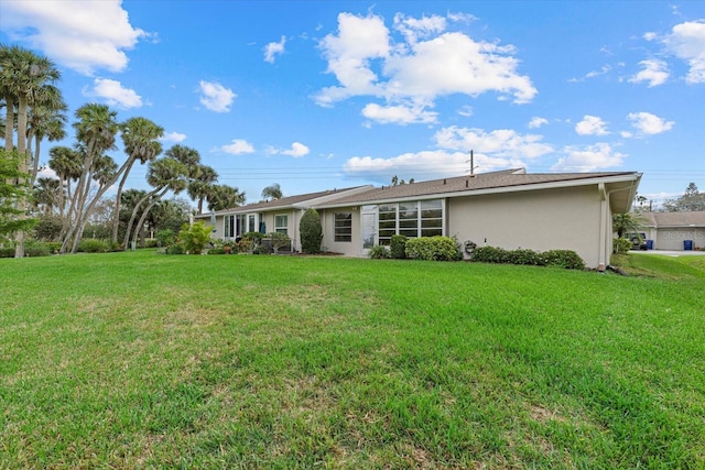 back of property with a yard and stucco siding