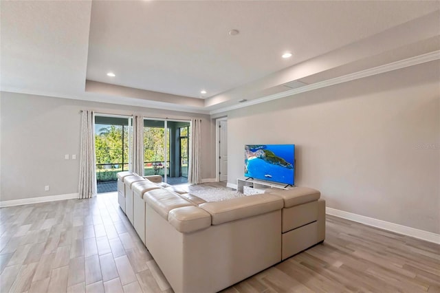 living area featuring light wood-style floors, baseboards, a tray ceiling, and recessed lighting