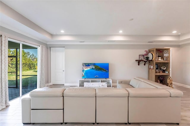 living area with baseboards, a raised ceiling, and recessed lighting