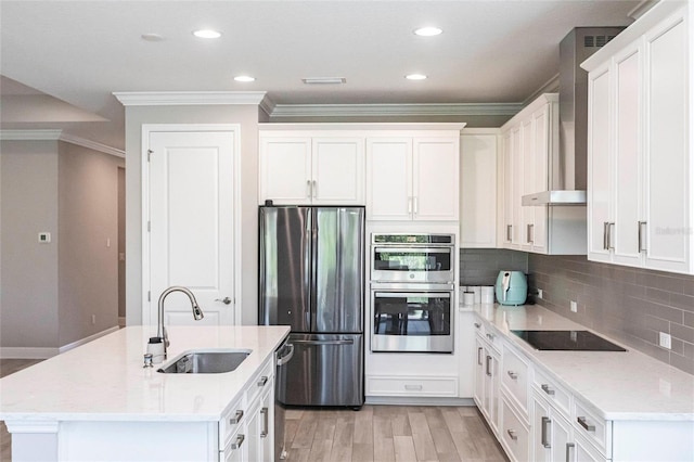 kitchen with wall chimney range hood, tasteful backsplash, appliances with stainless steel finishes, and a sink