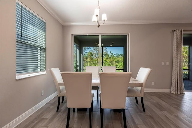 dining room with a notable chandelier, crown molding, baseboards, and wood finished floors