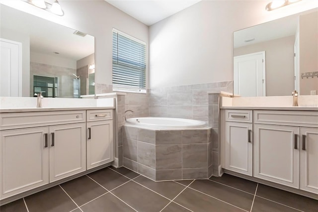 full bathroom featuring two vanities, a stall shower, a sink, tile patterned flooring, and a bath