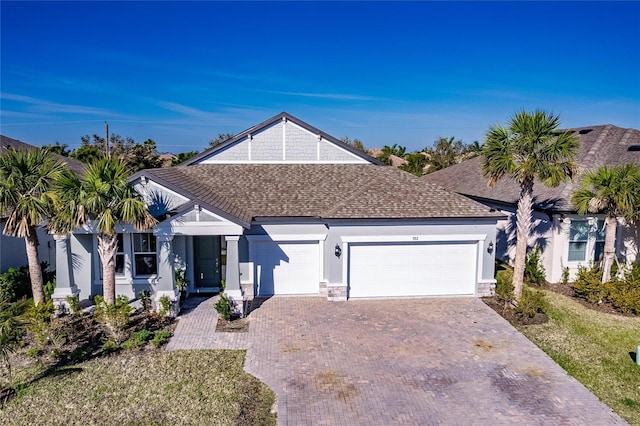 view of front of home featuring a shingled roof, decorative driveway, a garage, and stucco siding