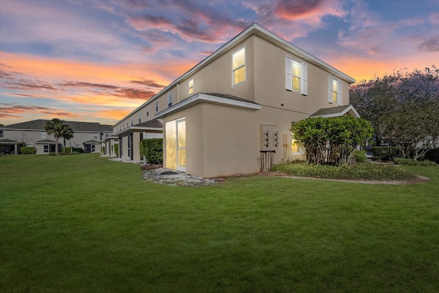 rear view of property with a lawn and stucco siding