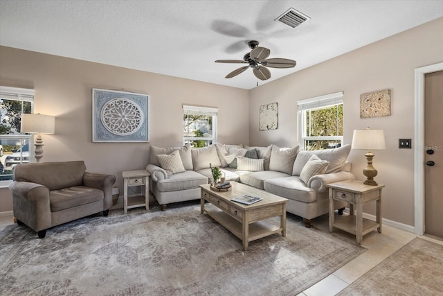 living room featuring light tile patterned floors, ceiling fan, a wealth of natural light, and visible vents