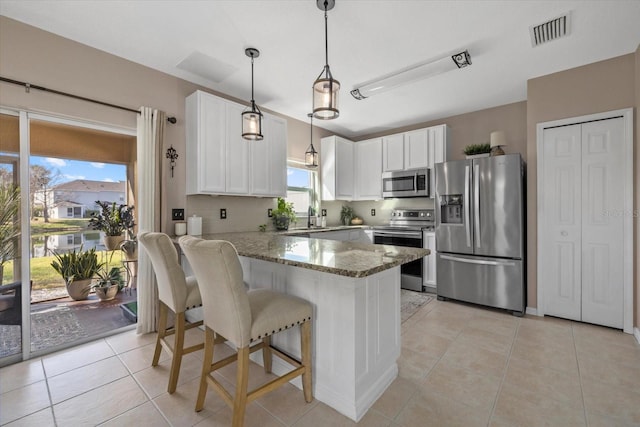 kitchen featuring stone countertops, visible vents, white cabinets, appliances with stainless steel finishes, and a peninsula