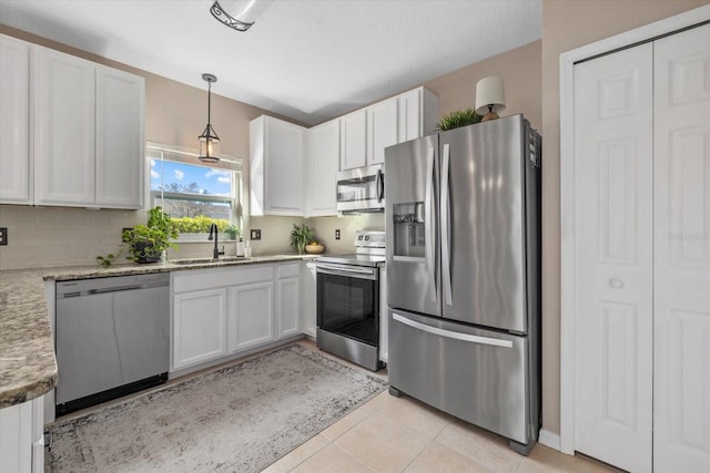 kitchen featuring appliances with stainless steel finishes, a sink, white cabinetry, backsplash, and light tile patterned flooring