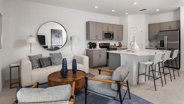 interior space with visible vents, a breakfast bar, open floor plan, gray cabinets, and stainless steel appliances