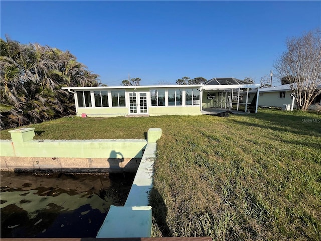 rear view of house featuring glass enclosure and a lawn