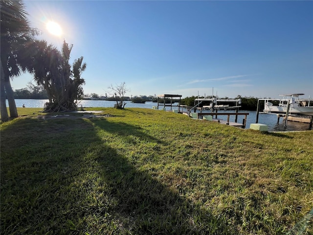 view of dock featuring a water view, a yard, and boat lift