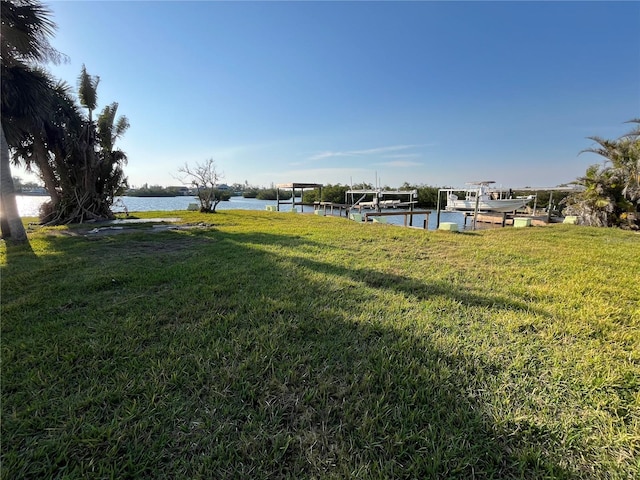 view of yard with a dock, a water view, and boat lift