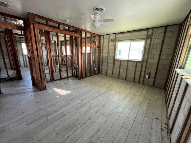 interior space with a textured ceiling, wood finished floors, visible vents, and a ceiling fan