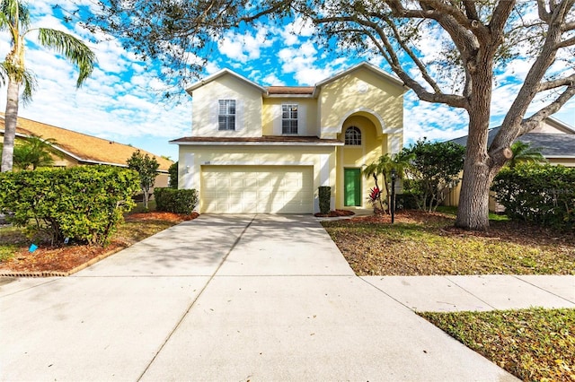 traditional home featuring concrete driveway, an attached garage, and stucco siding