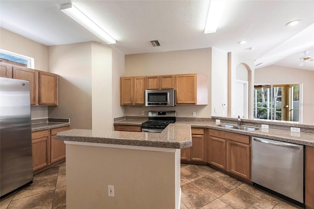 kitchen featuring visible vents, appliances with stainless steel finishes, stone countertops, a sink, and a kitchen island