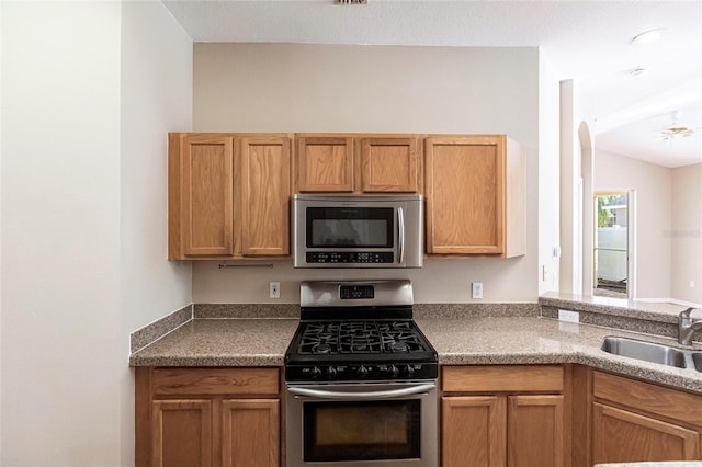 kitchen with lofted ceiling, appliances with stainless steel finishes, and a sink