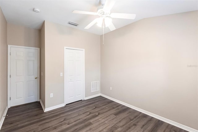 unfurnished bedroom with dark wood-type flooring, a closet, visible vents, and baseboards