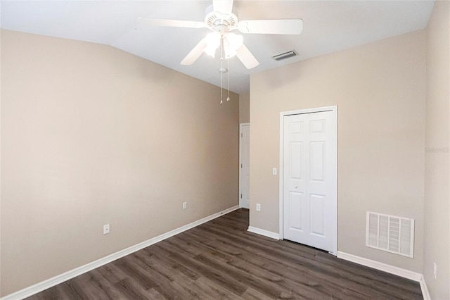 unfurnished bedroom featuring dark wood finished floors, a closet, visible vents, vaulted ceiling, and baseboards