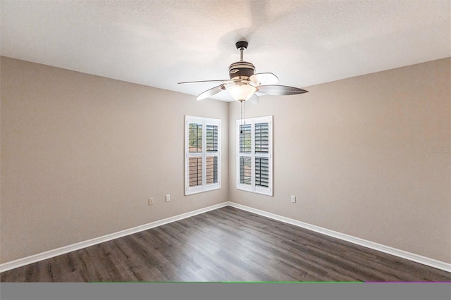 spare room with dark wood-style floors, a textured ceiling, baseboards, and a ceiling fan