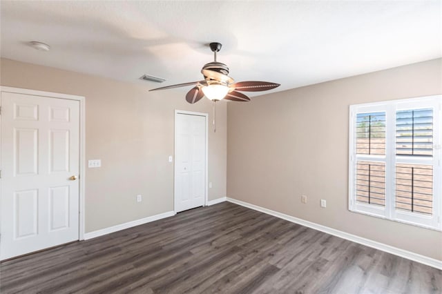 unfurnished bedroom featuring dark wood-type flooring, a closet, visible vents, and baseboards