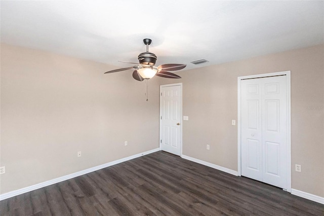 unfurnished bedroom with baseboards, visible vents, a ceiling fan, dark wood-style flooring, and a closet