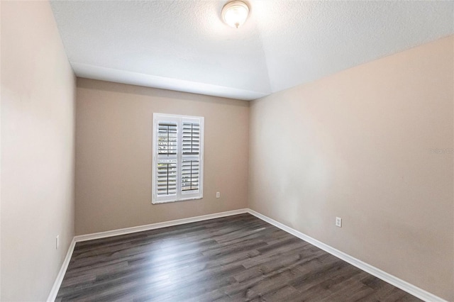 unfurnished room with dark wood-style floors, baseboards, vaulted ceiling, and a textured ceiling