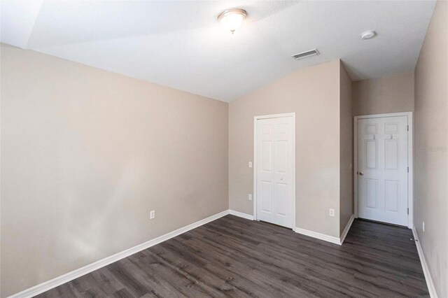 unfurnished bedroom featuring lofted ceiling, a closet, baseboards, and dark wood-style flooring