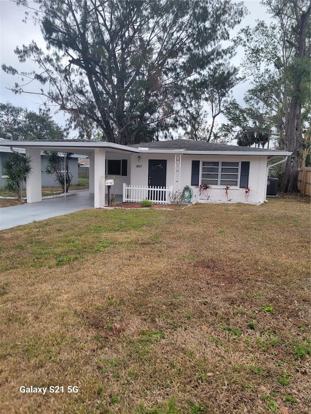 ranch-style home with an attached carport, a front yard, driveway, a porch, and stucco siding