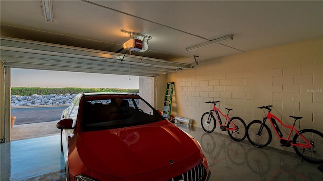 garage with a garage door opener and concrete block wall