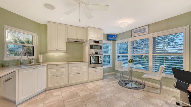 kitchen featuring appliances with stainless steel finishes, a sink, light countertops, under cabinet range hood, and backsplash