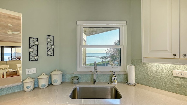 kitchen with tasteful backsplash, white cabinets, light countertops, and a sink