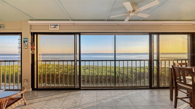 sunroom / solarium with ceiling fan and a water view