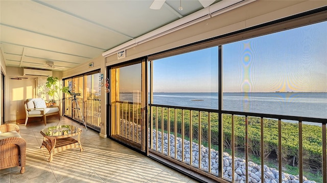 sunroom featuring a ceiling fan, an AC wall unit, a water view, and plenty of natural light