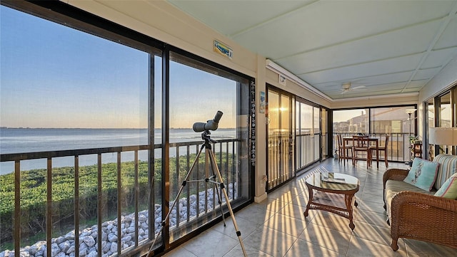 sunroom / solarium featuring a water view and a ceiling fan