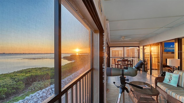 sunroom / solarium featuring ceiling fan and a water view