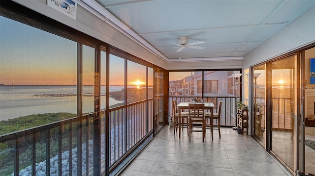 unfurnished sunroom with a water view and a ceiling fan