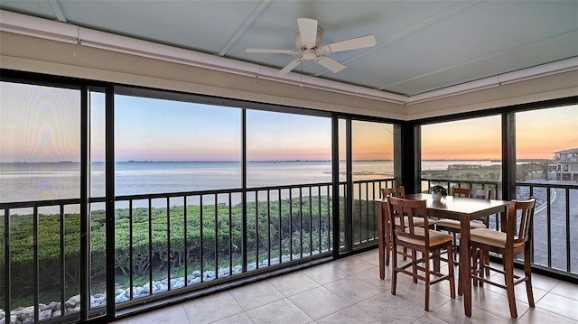 sunroom / solarium featuring a water view and ceiling fan