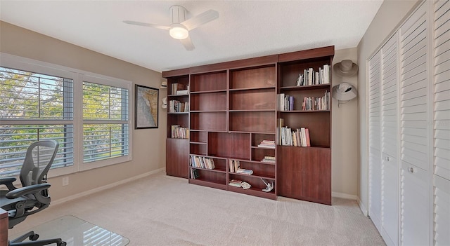 carpeted office space featuring ceiling fan, a textured ceiling, and baseboards