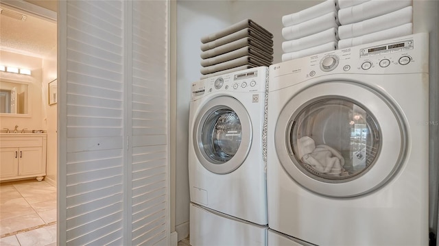 washroom featuring a textured ceiling, light tile patterned flooring, a sink, and washing machine and clothes dryer