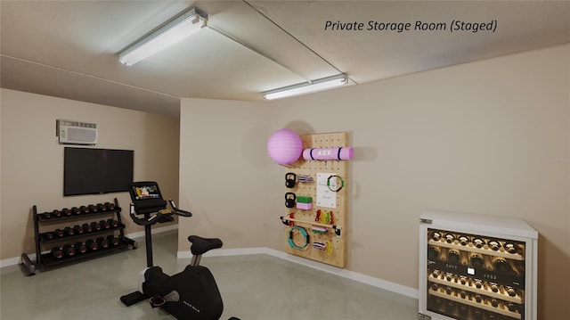 exercise room with baseboards and a wall mounted air conditioner